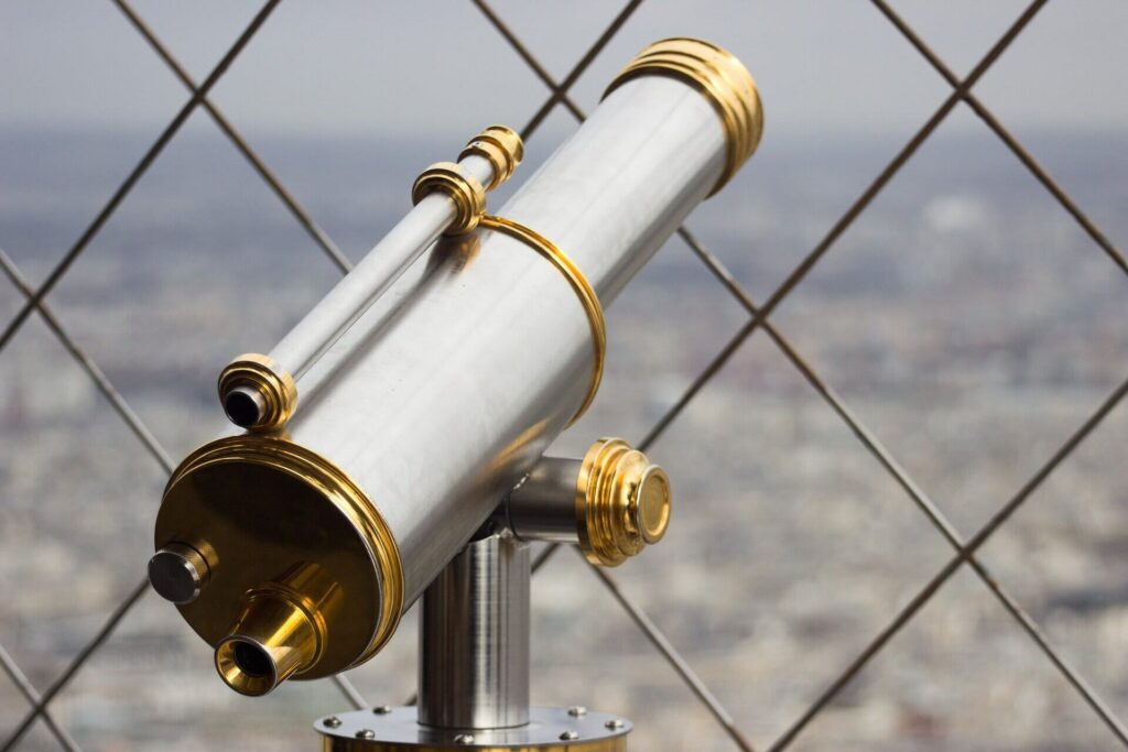 Alida Miranda-Wolff, How to Build Affinity Groups article image, silver and gold telescope in front of a blurred city background